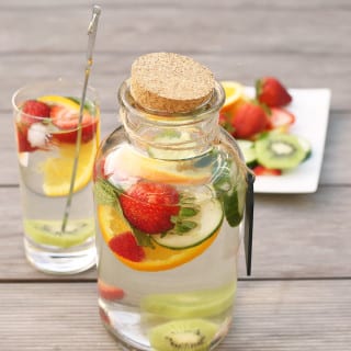 Super healthy Flavored Fruit Water infused with sliced strawberries, orange slices, cucumber, mint and kiwi. The perfect refreshing drink on a warm day! No artificial ingredients added. #fruitwater #fruit #drink #strawberries #oranges #cucumbers #water #healthy #vegan #detox