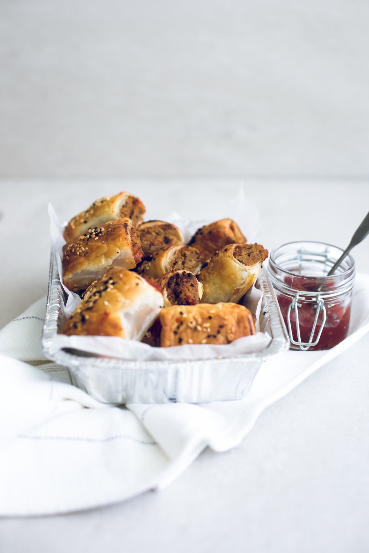 Delicious Vegan Tofu Sausage Rolls - Tofu and Nut Sausage Mince encased in golden and flaky Puff Pastry, served with Tomato Sauce. Perfect for parties and picnics. #vegan #tofu #sausagerolls #vegansausagerolls #simple #delicious #puffpastry #nuts 