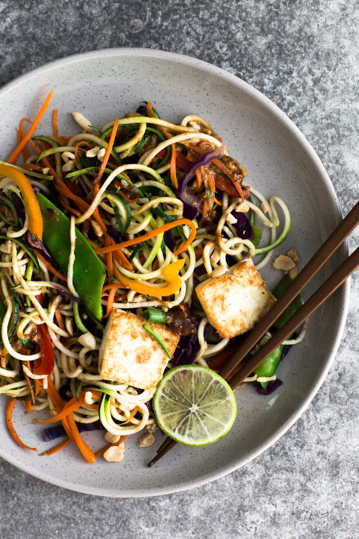 Delicious, healthy and light Asian Rainbow Zucchini Noodles with Crispy Tofu and an Almond Butter Dressing. Vegan, Gluten Free, Ready in Under 25 minutes. #vegan #zucchini #zoodle #padthai #vegetarian #lowcarb #tofu #peppers #healthy #simple #asian #almondbutter #dressing #glutenfree