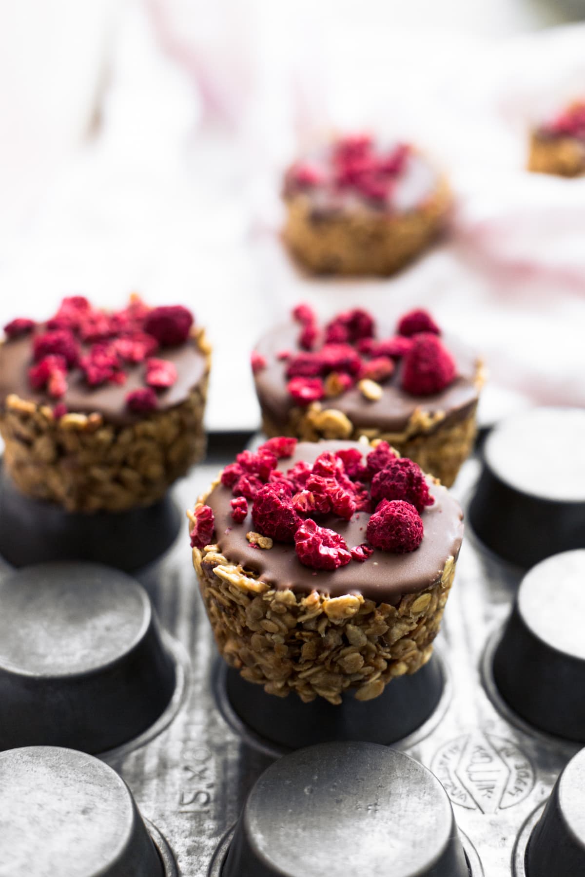 Simple No-Bake Vegan Granola Cups filled with Nut Butter of your choice and topped off with Chocolate. Read in under an hour. #vegan #granola #oats #chocolate #snacks #healthy #peanutbutter #nobake #slice #fridge #veganrecipes
