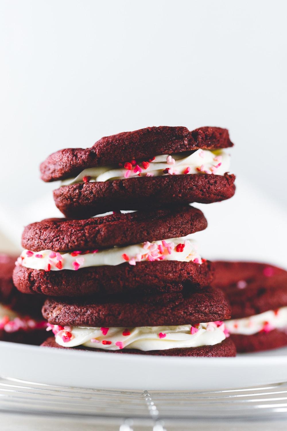 Delicious and chewy Vegan Red Velvet Cookies sandwiched with a yummy Cream Cheese Frosting. Think Red Velvet Cake, but in a convenient cookie form! #redvelvet #cookies #veganredvelvet #vegancookies #cheesecake #creamcheese #icing #dairyfree #eggless #cake #simple #easy #baking