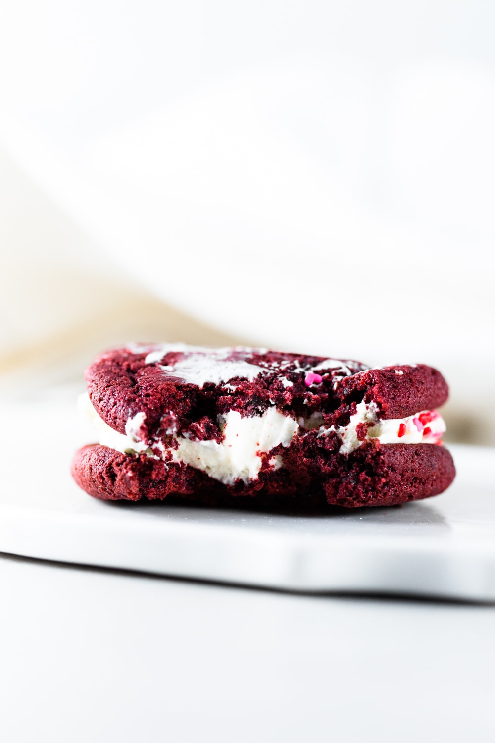 Delicious and chewy Vegan Red Velvet Cookies sandwiched with a yummy Cream Cheese Frosting. Think Red Velvet Cake, but in a convenient cookie form! #redvelvet #cookies #veganredvelvet #vegancookies #cheesecake #creamcheese #icing #dairyfree #eggless #cake #simple #easy #baking