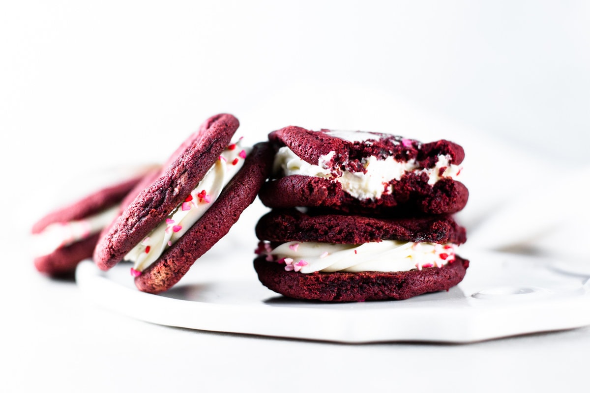 Delicious and chewy Vegan Red Velvet Cookies sandwiched with a yummy Cream Cheese Frosting. Think Red Velvet Cake, but in a convenient cookie form! #redvelvet #cookies #veganredvelvet #vegancookies #cheesecake #creamcheese #icing #dairyfree #eggless #cake #simple #easy #baking