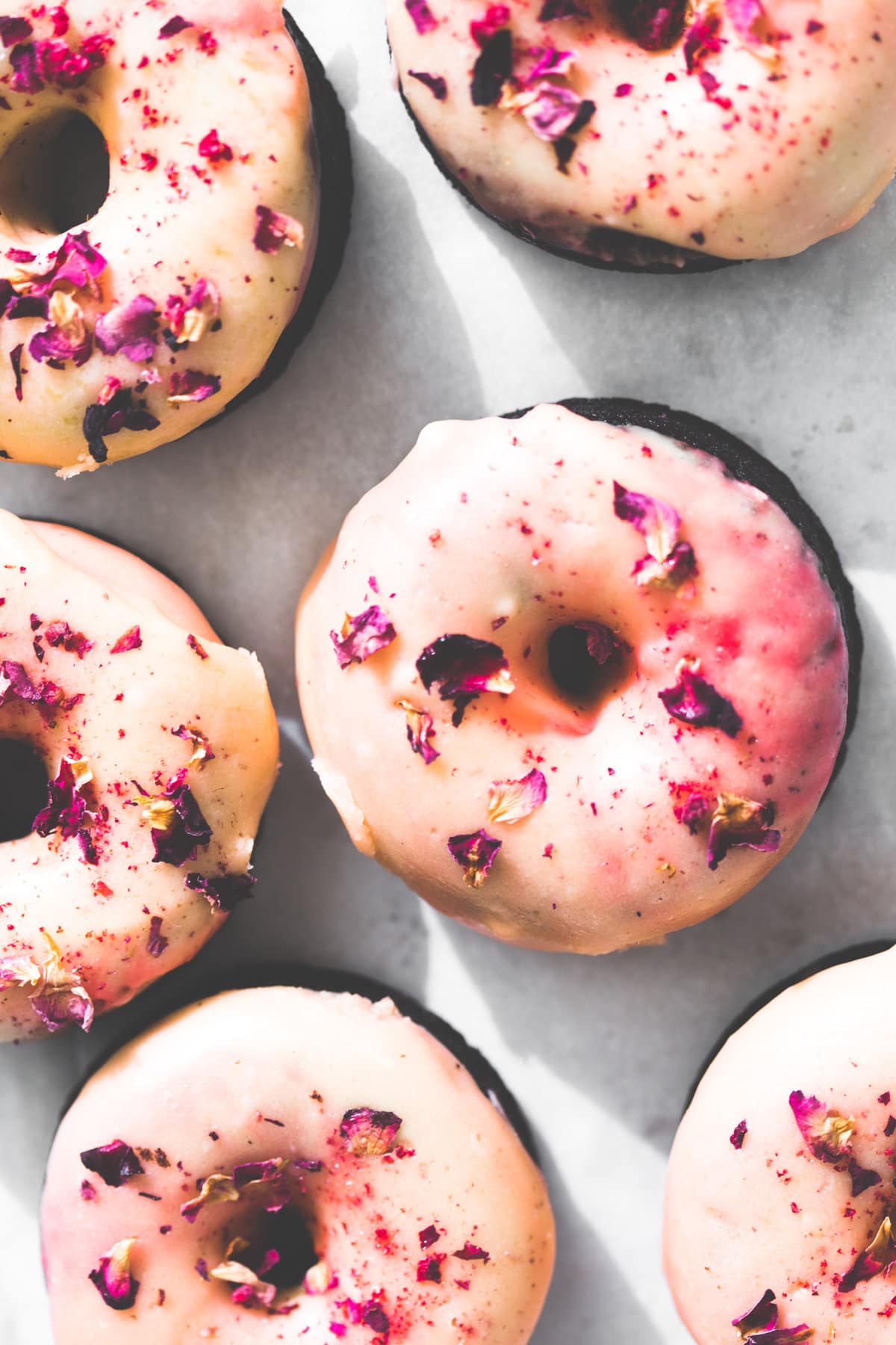 Moist and delicious Vegan Baked Chocolate Donuts topped with a floral Rose Glaze. Easy to make and ready in under 30 minutes. #donuts #vegandonuts #cakedonuts #bakeddonuts #turkishdelight #chocolate #chocolatedonuts #baking #vegetarian #chocolatecake #easy #30minutes