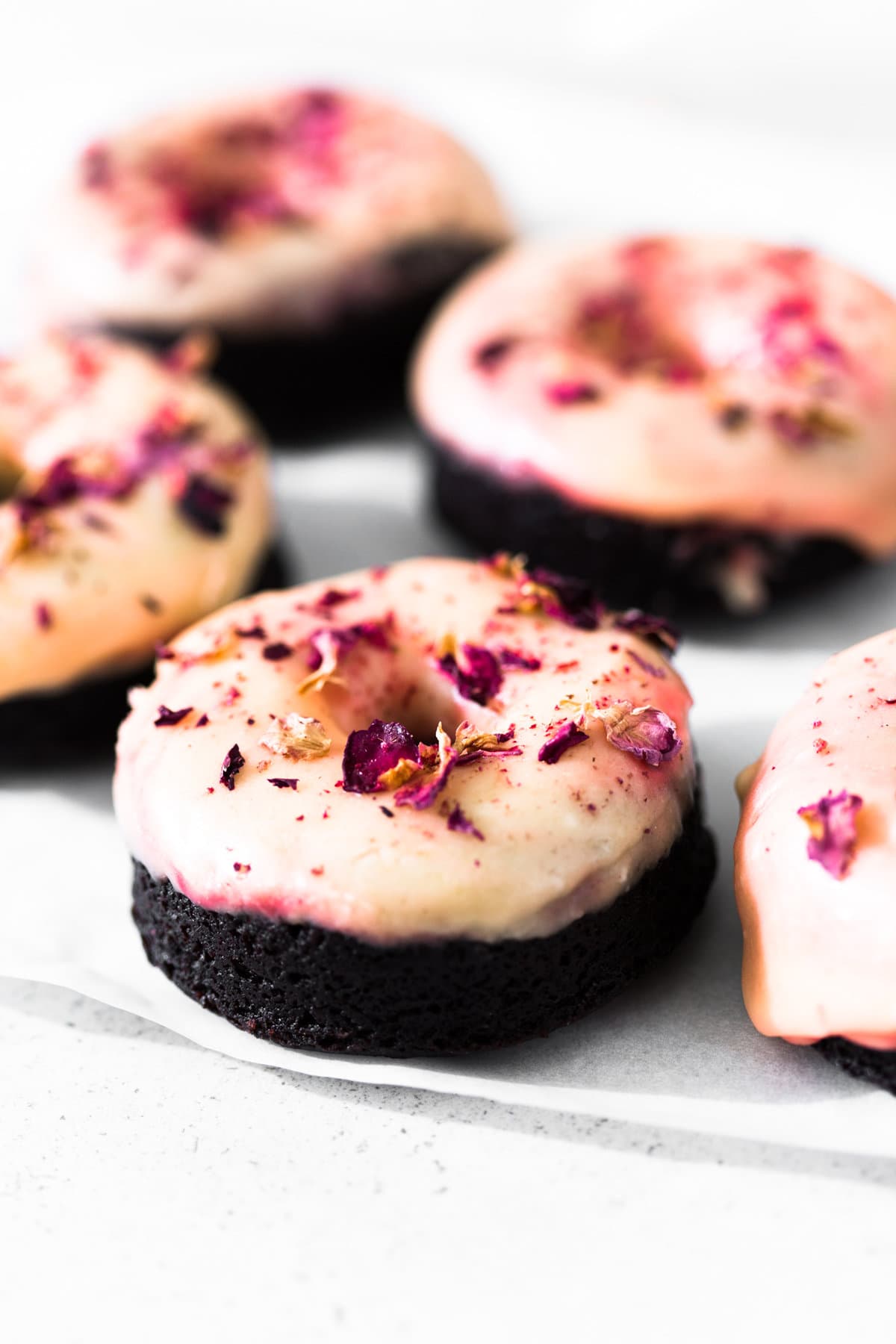 Moist and delicious Vegan Baked Chocolate Donuts topped with a floral Rose Glaze. Easy to make and ready in under 30 minutes. #donuts #vegandonuts #cakedonuts #bakeddonuts #turkishdelight #chocolate #chocolatedonuts #baking #vegetarian #chocolatecake #easy #30minutes