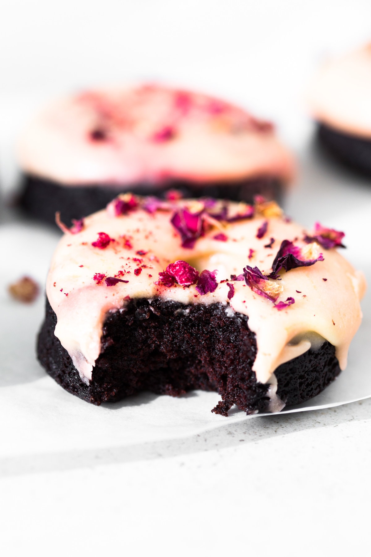 Moist and delicious Vegan Baked Chocolate Donuts topped with a floral Rose Glaze. Easy to make and ready in under 30 minutes. #donuts #vegandonuts #cakedonuts #bakeddonuts #turkishdelight #chocolate #chocolatedonuts #baking #vegetarian #chocolatecake #easy #30minutes
