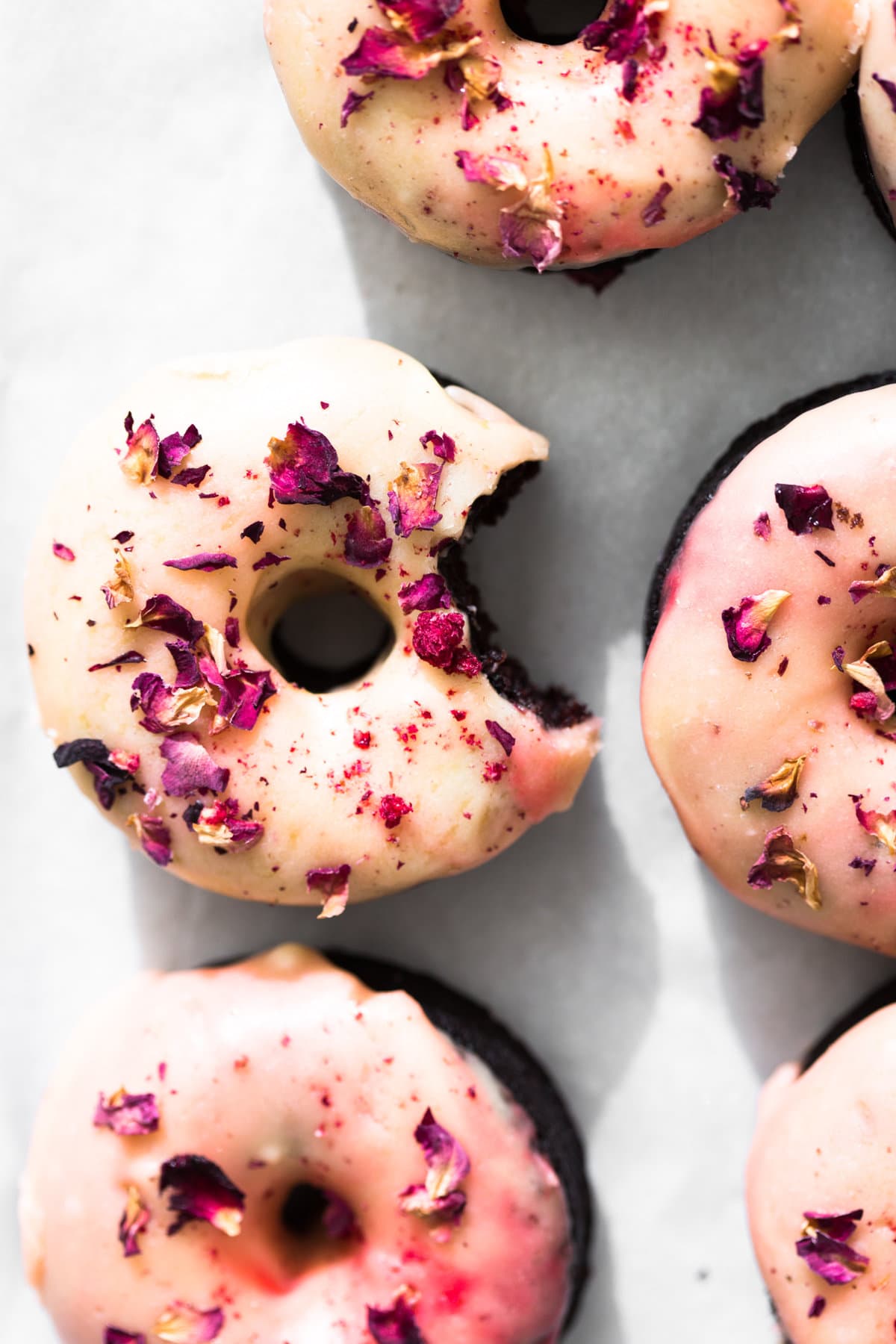 Moist and delicious Vegan Baked Chocolate Donuts topped with a floral Rose Glaze. Easy to make and ready in under 30 minutes. #donuts #vegandonuts #cakedonuts #bakeddonuts #turkishdelight #chocolate #chocolatedonuts #baking #vegetarian #chocolatecake #easy #30minutes